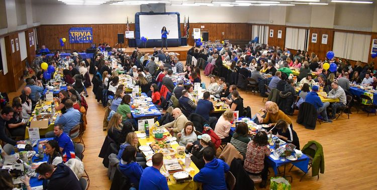 A large group of people in a large hall participating in a Trivia Night contest.