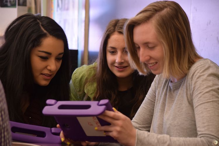 Three students working on a tablet.