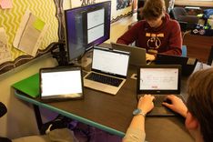 Students sitting around laptops having a discussion.