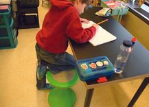 Student writing in a notebook at a desk.