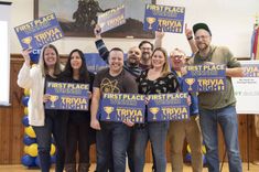 A group of people holding signs that say First Place at CFEE's Annual Trivia Night.