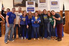 A group of people holding a trophy for winning the 2020 CFEE Trivia Night.