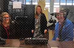 Tara O’Connor and Bernie Wagenblast sitting behind two podcasting microphones smiling for the camera.